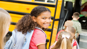 A kid walking in line to get on a school bus
