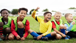 Boys sitting in a line on the grass in sportswear
